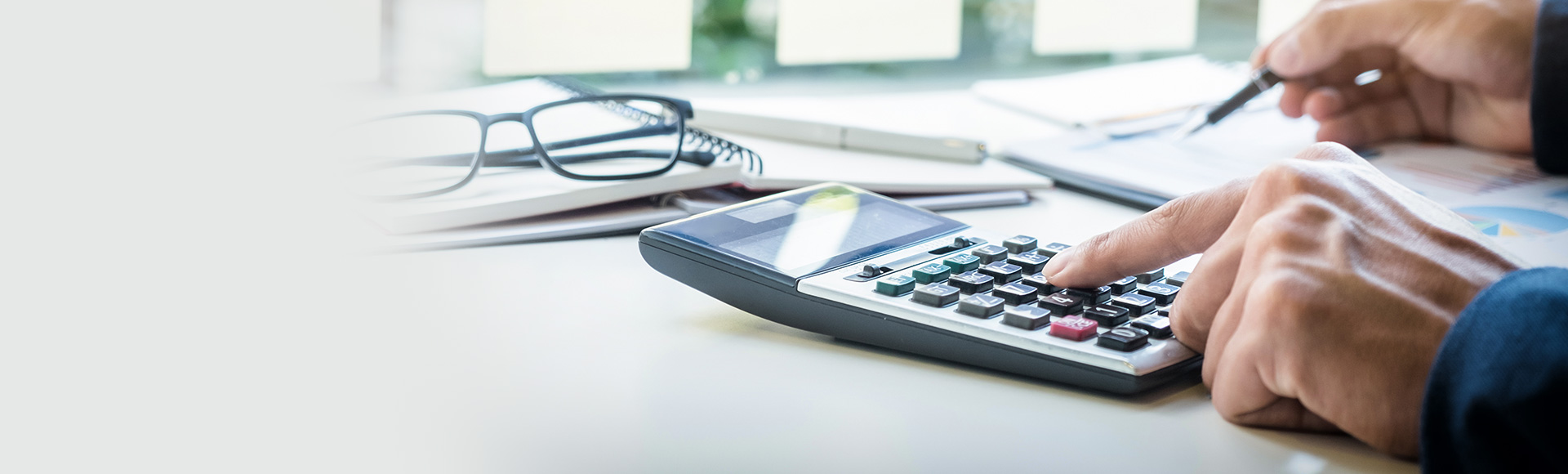 close-up of a man using a calculator on a desk