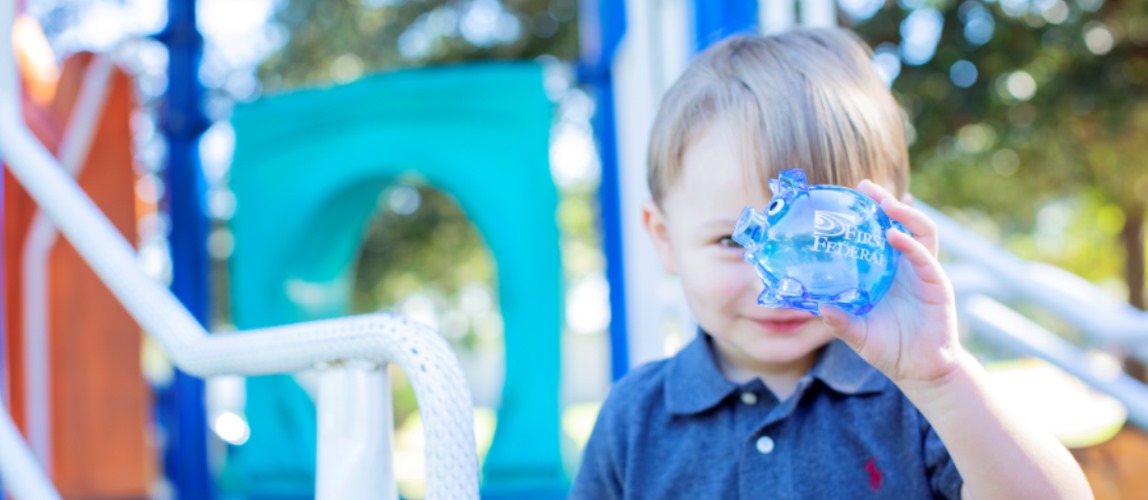 young child holding up a First Federal piggy bank