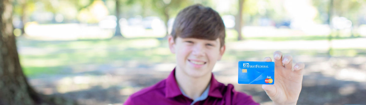 Kid holding up a FirstFederal credit card